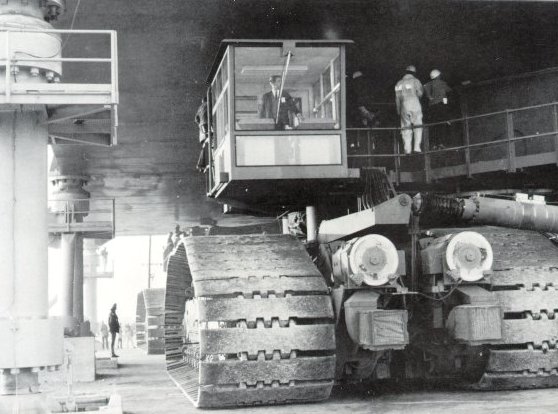 A photo of a driver eases the crawler beneath a Mobile Launcher